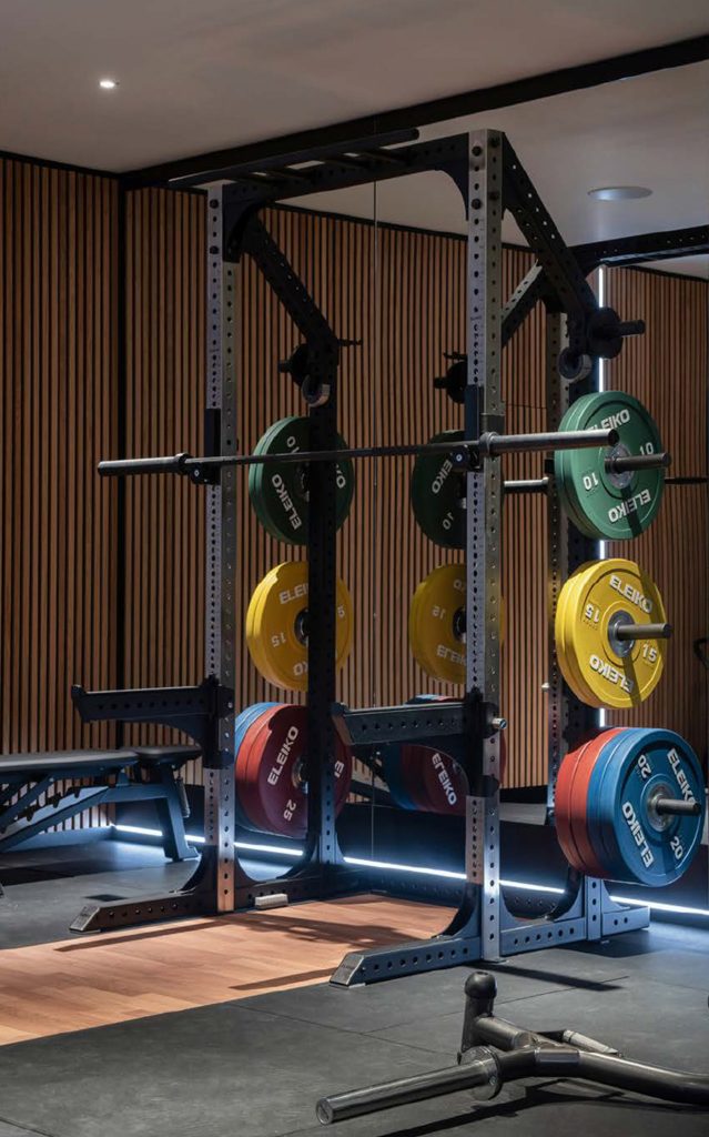 Luxury home gym design in Birmingham featuring a half rack with sport training plates &ndash; OOSH Ltd